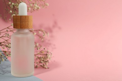 Bottle of face serum and beautiful flowers on color background, closeup. Space for text