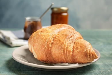 Plate with tasty croissant on wooden background