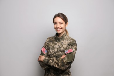 Portrait of happy female cadet on light grey background