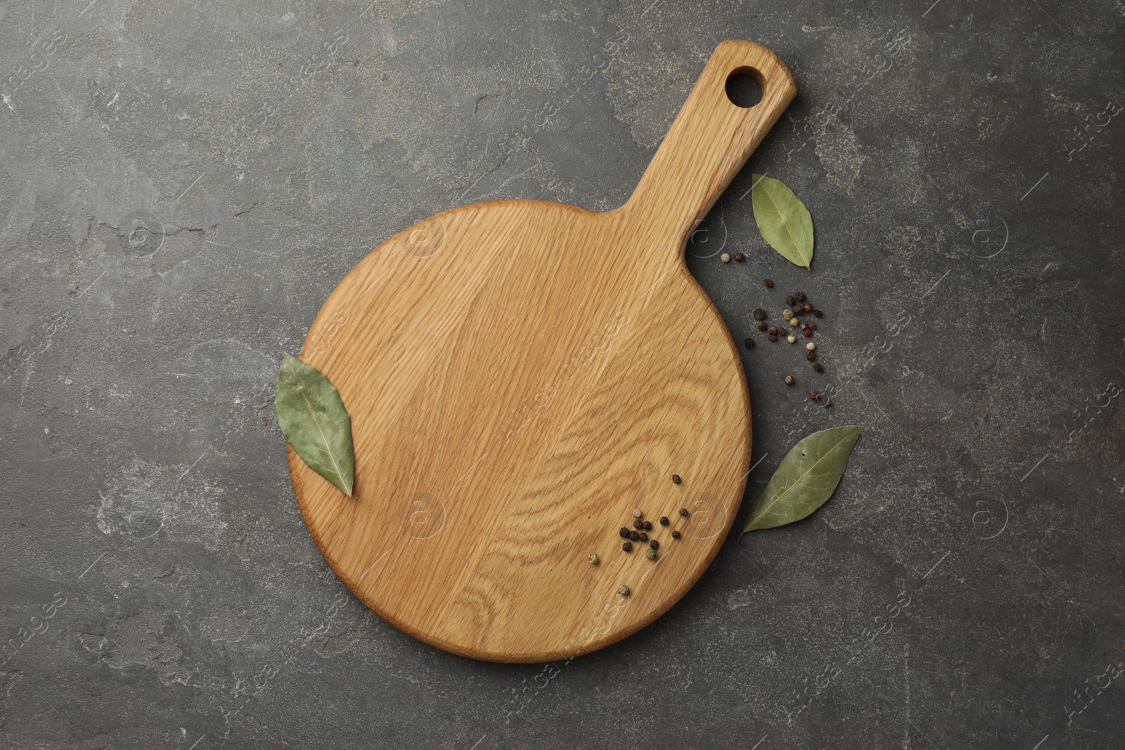 Photo of Cutting board, pepper and bay leaves on grey table, flat lay. Space for text