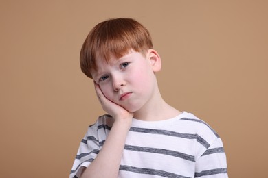 Photo of Portrait of sad little boy on beige background