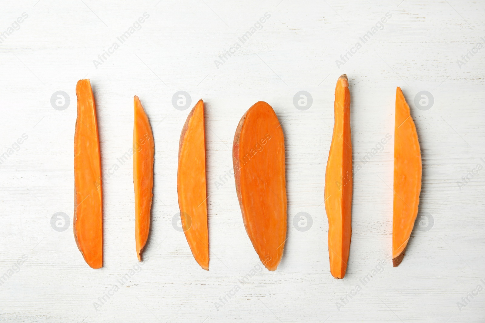 Photo of Flat lay composition with slices of sweet potato on white wooden background