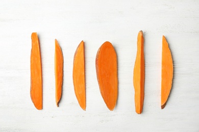 Photo of Flat lay composition with slices of sweet potato on white wooden background