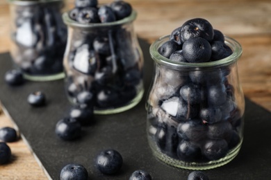 Photo of Jars of fresh acai berries on black board, closeup. Space for text