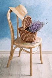 Photo of Wicker basket with lavender flowers on chair indoors