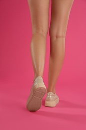 Photo of Woman wearing shoes on pink background, closeup