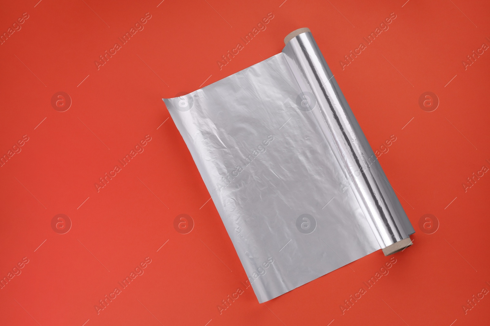 Photo of Roll of aluminum foil on orange background, top view