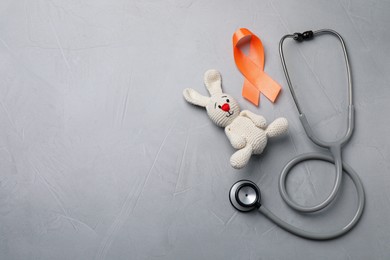 Photo of Orange ribbon, toy bunny and stethoscope on light grey table, flat lay with space for text. Multiple sclerosis awareness