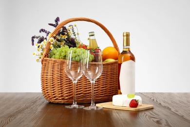 Photo of Picnic basket with wine and products on wooden table against white background