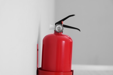 Photo of Red fire extinguisher on light grey wall