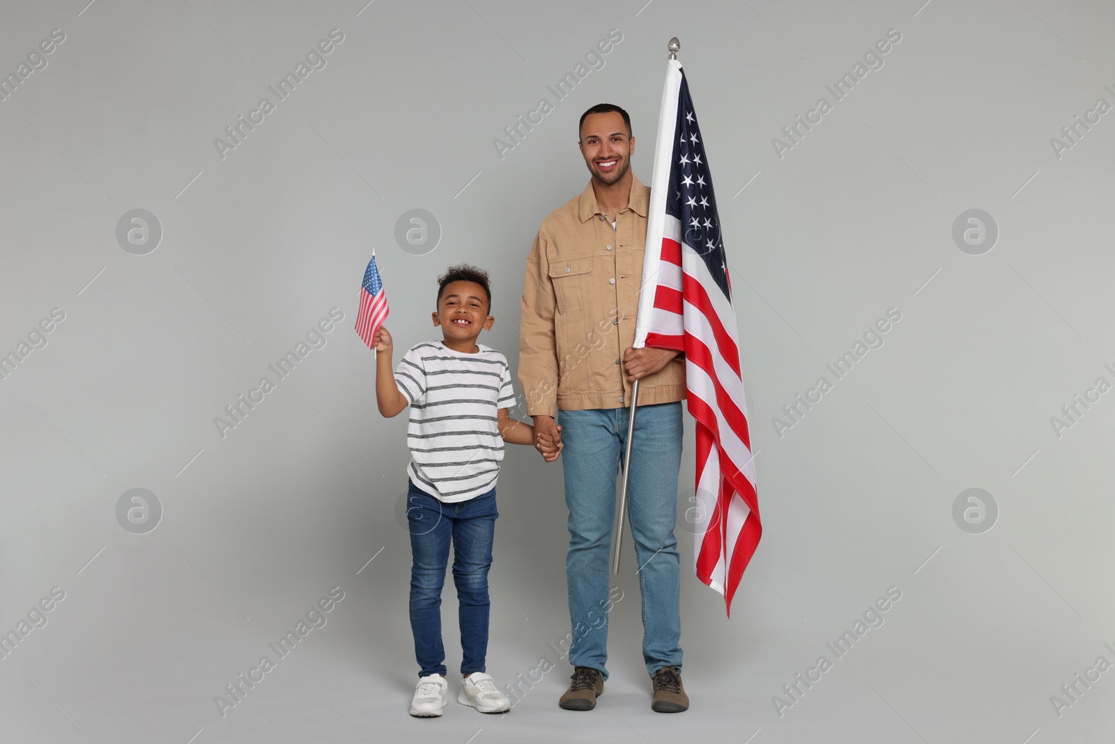 Photo of 4th of July - Independence Day of USA. Happy man and his son with American flags on light grey background