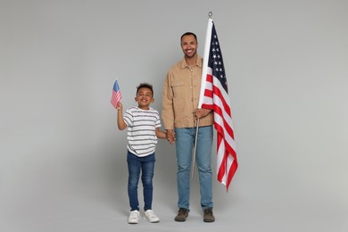 4th of July - Independence Day of USA. Happy man and his son with American flags on light grey background