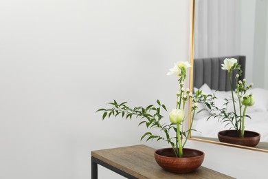 Photo of Stylish ikebana with beautiful flowers and green branch carrying cozy atmosphere at home, space for text