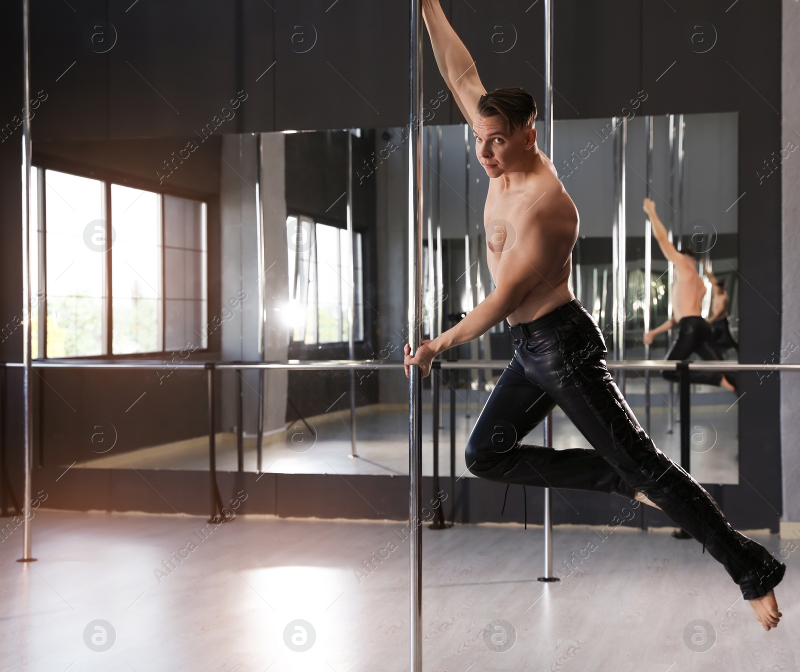 Photo of Attractive young man dancing in studio with poles