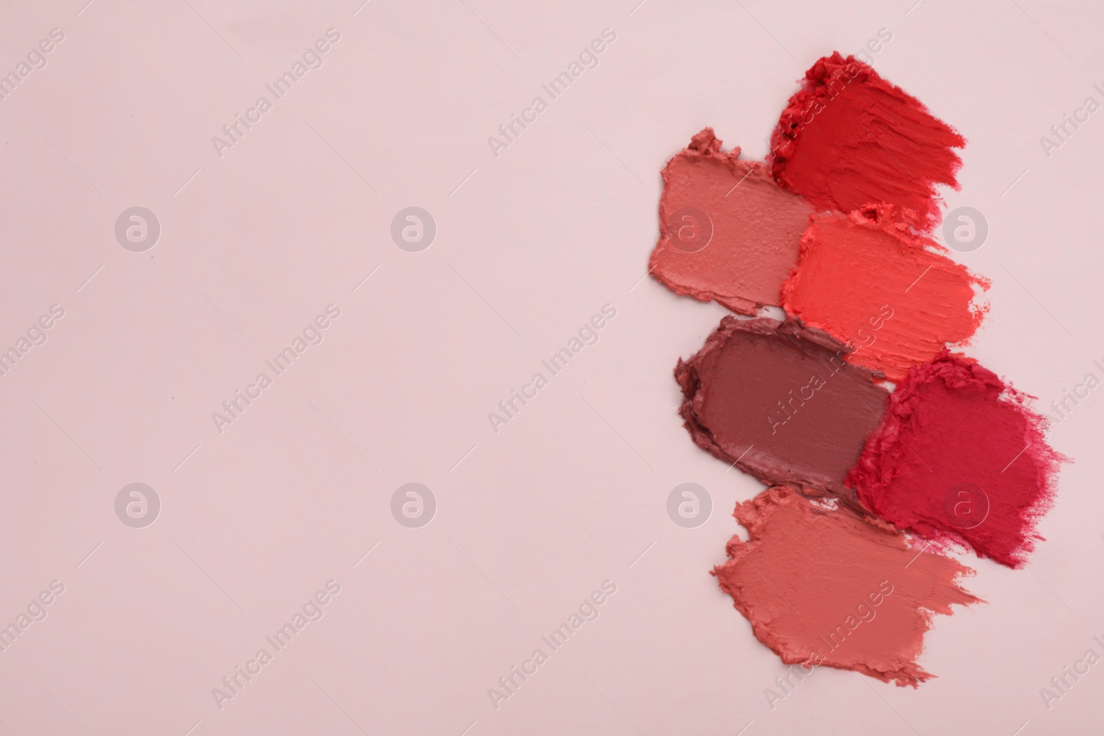 Photo of Smears of different beautiful lipsticks on light background, top view. Space for text