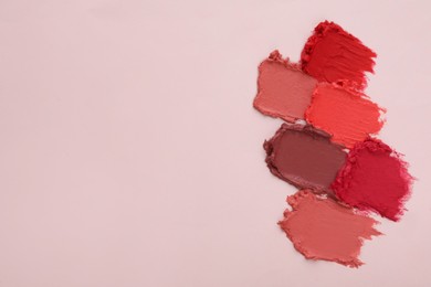 Smears of different beautiful lipsticks on light background, top view. Space for text