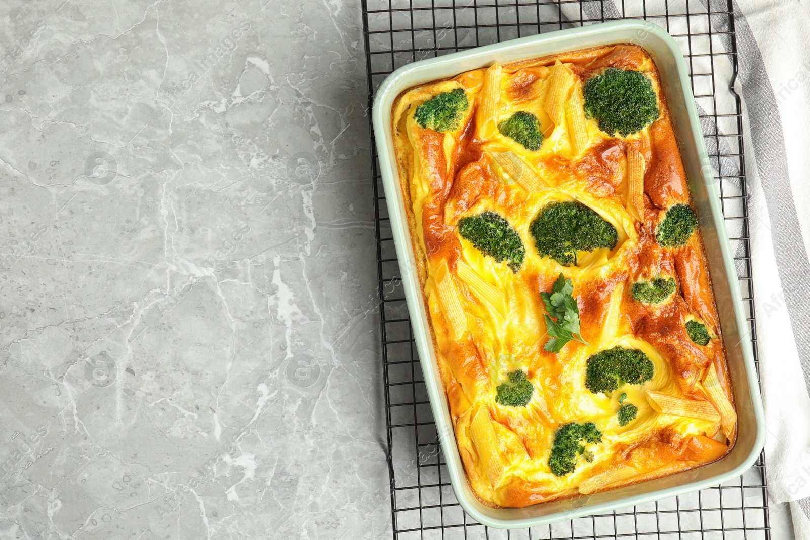 Photo of Tasty broccoli casserole in baking dish on cooling rack, top view. Space for text