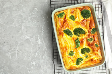 Photo of Tasty broccoli casserole in baking dish on cooling rack, top view. Space for text