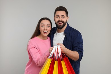 Photo of Excited couple with shopping bags on grey background