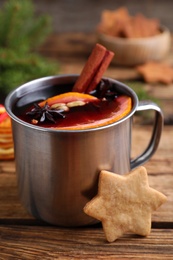 Aromatic mulled wine and cookie on wooden table, closeup