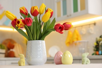 Bouquet of tulips and Easter decorations on white table indoors, closeup