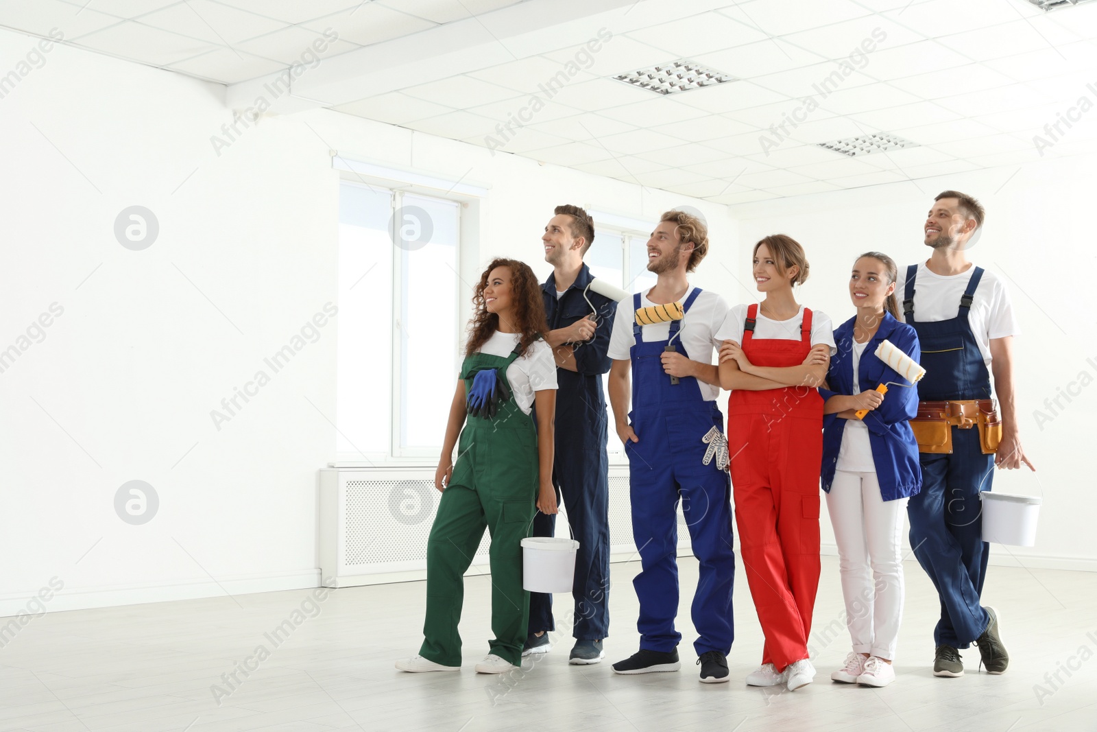 Photo of Team of professional painters with tools working indoors