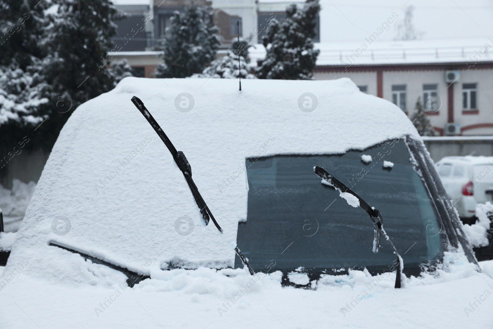 Photo of Car with windscreen wipers covered with snow outdoors on winter day