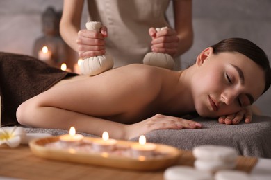 Spa therapy. Beautiful young woman lying on table during herbal bag massage in salon