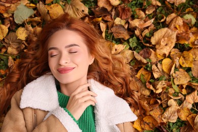 Beautiful woman lying among autumn leaves outdoors, top view. Space for text