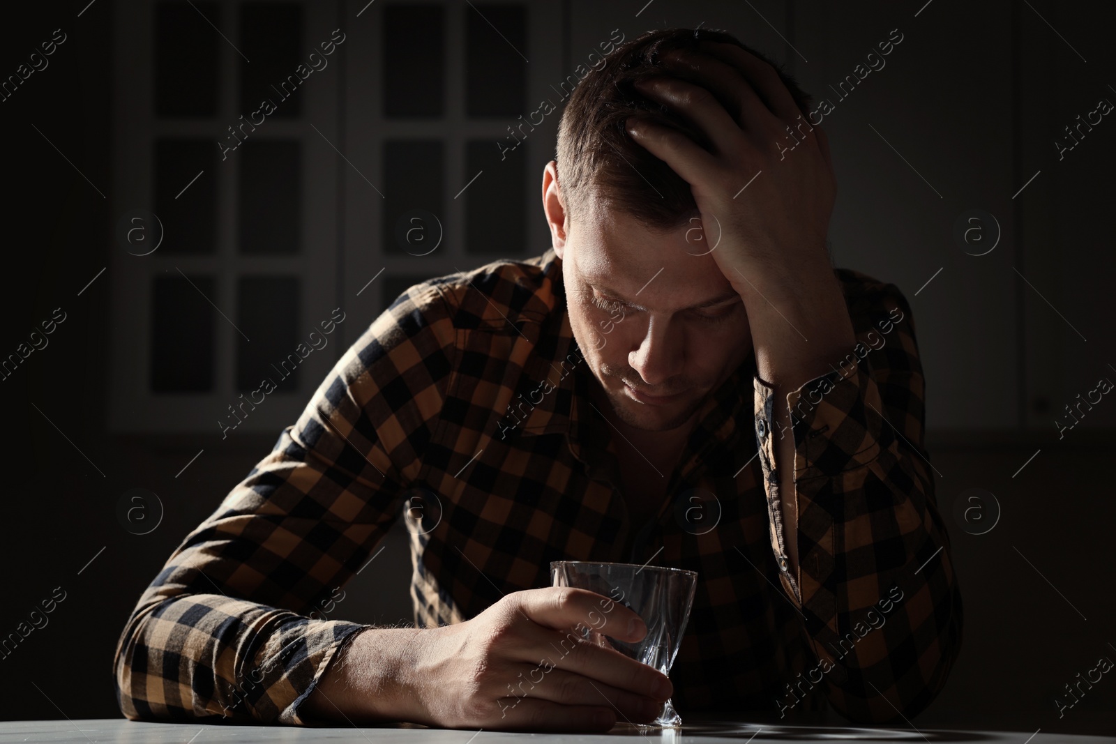 Photo of Addicted man with alcoholic drink at table in kitchen