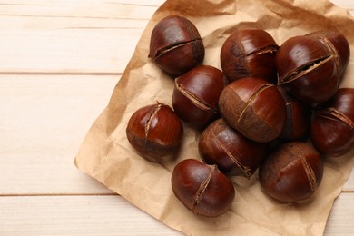Photo of Roasted edible sweet chestnuts on wooden table, flat lay. Space for text