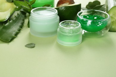 Photo of Homemade cosmetic products and fresh ingredients on light green background, closeup. Space for text