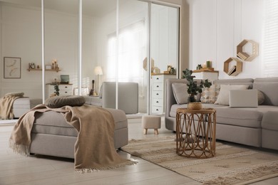 Comfortable grey sofa, ottoman and wardrobe with mirror doors in living room interior