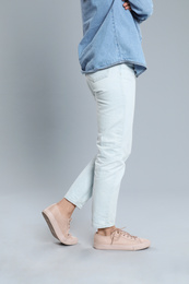 Photo of Young woman in stylish jeans on grey background, closeup