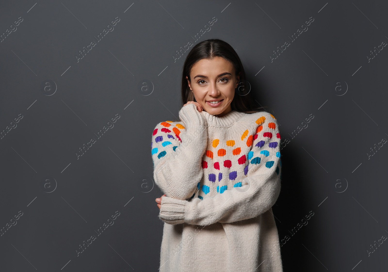 Photo of Beautiful young woman in warm sweater on dark background