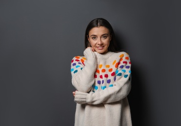 Photo of Beautiful young woman in warm sweater on dark background