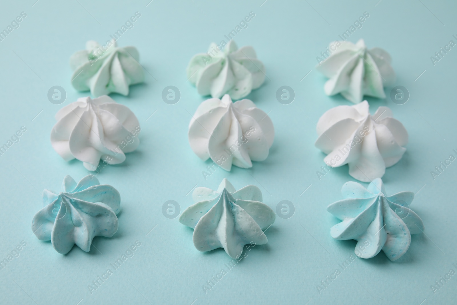 Photo of Delicious meringue cookies on light blue background, closeup