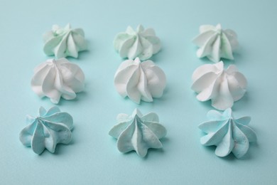 Photo of Delicious meringue cookies on light blue background, closeup