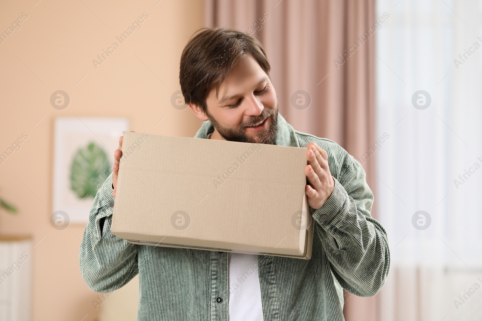 Photo of Man with parcel at home. Internet shopping