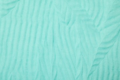 Photo of Texture of turquoise crumpled fabric as background, top view