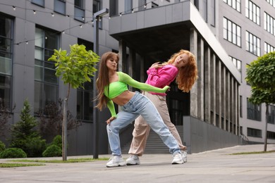 Beautiful young women dancing hip hop outdoors, low angle view
