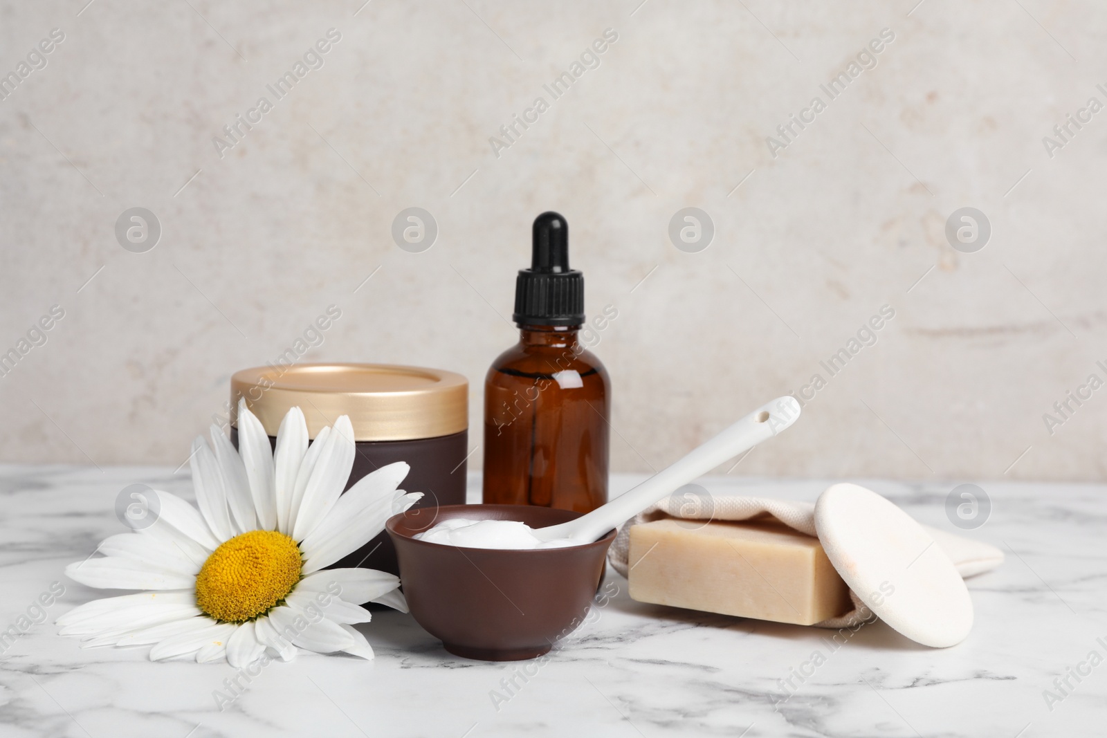 Photo of Composition with chamomile flower and cosmetic products on white marble table