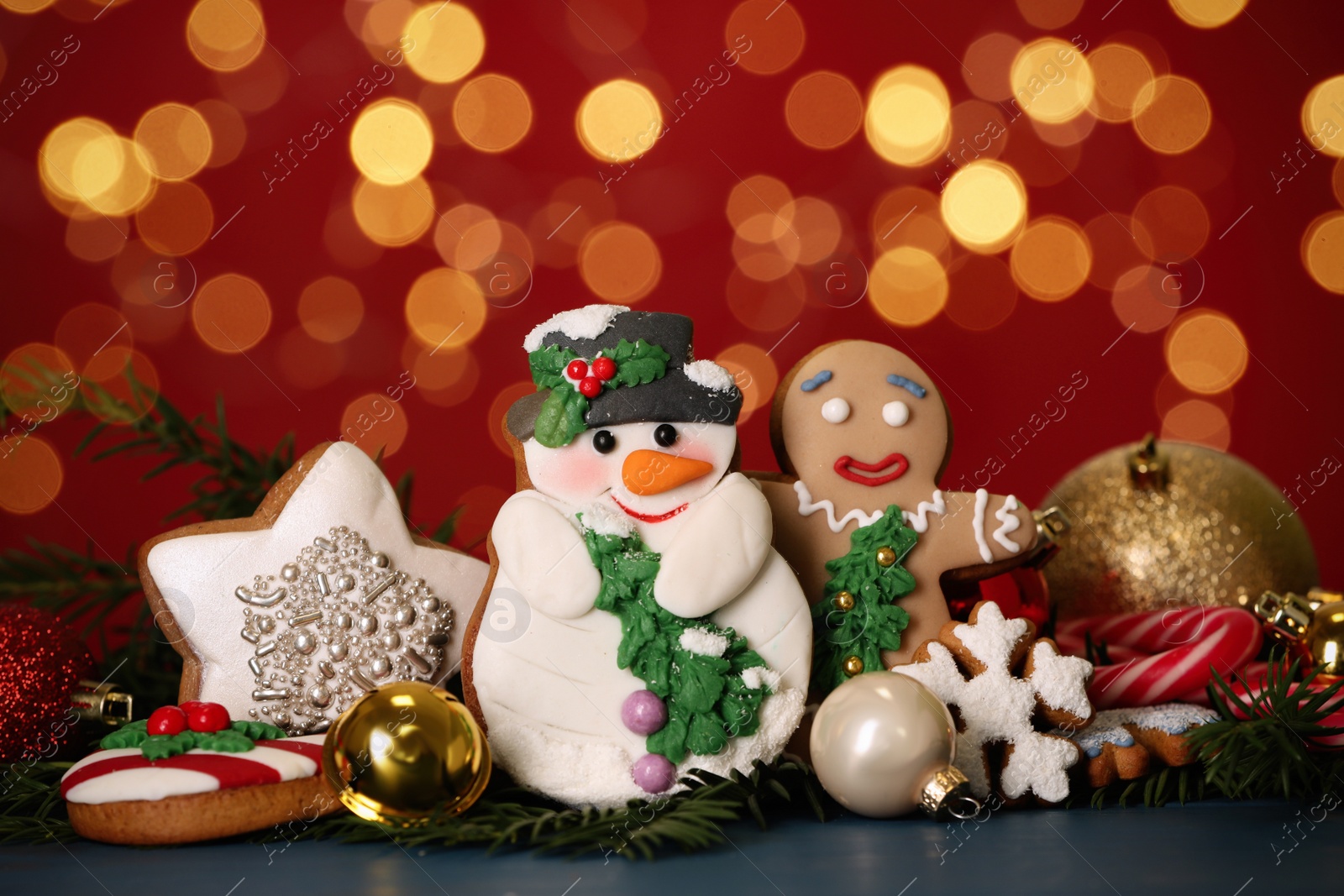 Photo of Sweet Christmas cookies and decor on dark table against blurred festive lights