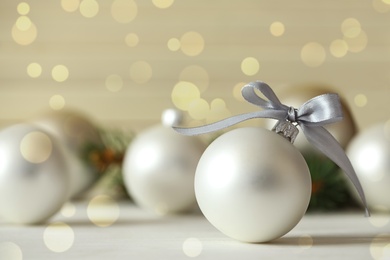 Image of Beautiful Christmas ball with silver bow on table, bokeh effect