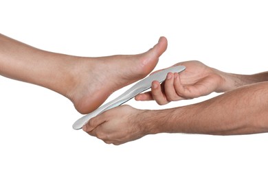 Orthopedist fitting insole to patient's foot on white background, closeup