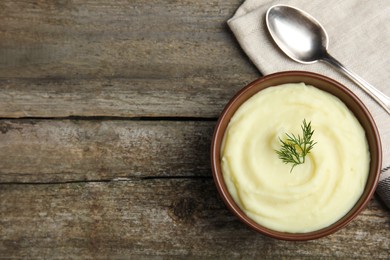 Photo of Freshly cooked homemade mashed potatoes with spoon and napkin on wooden table, top view. Space for text