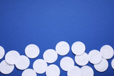 Photo of Many cotton pads on blue background, flat lay. Space for text