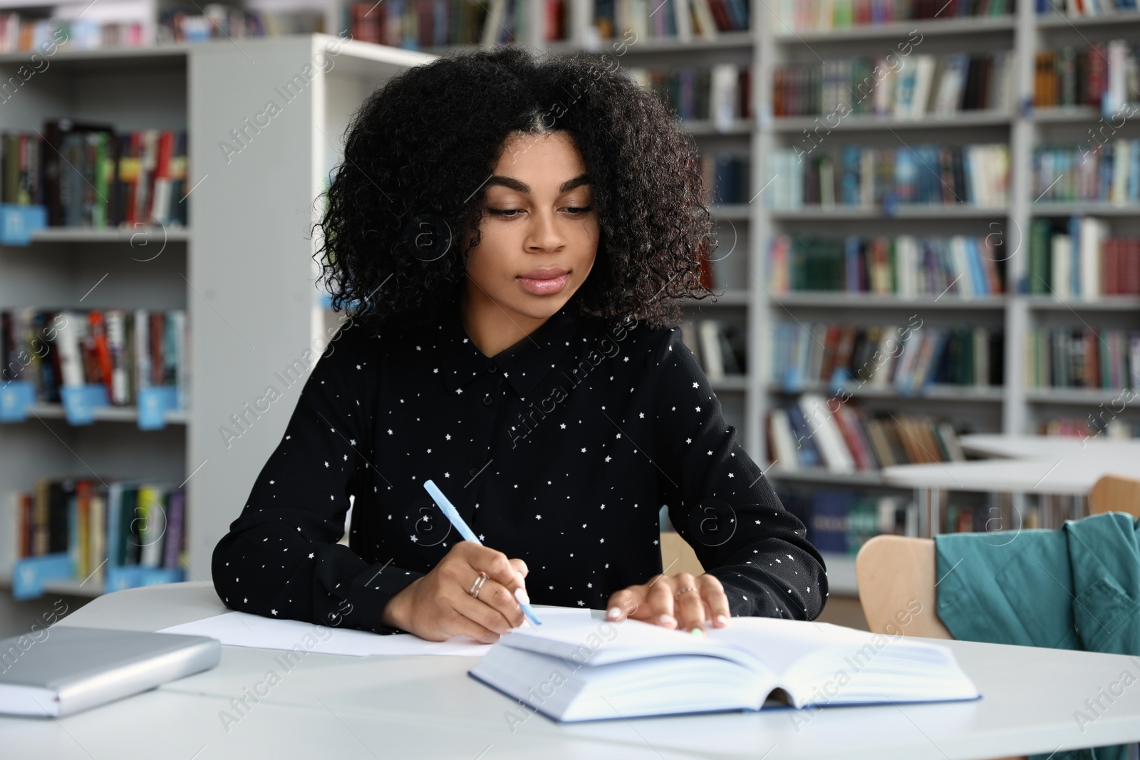 Photo of Young African-American woman studying at table in library