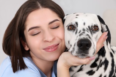 Photo of Beautiful woman with her adorable Dalmatian dog indoors, closeup. Lovely pet