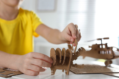 Little boy making carton toys at table indoors, closeup. Creative hobby